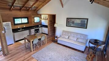 Un interior acogedor con techo de madera, un sofá, una mesa de comedor y una zona de cocina.