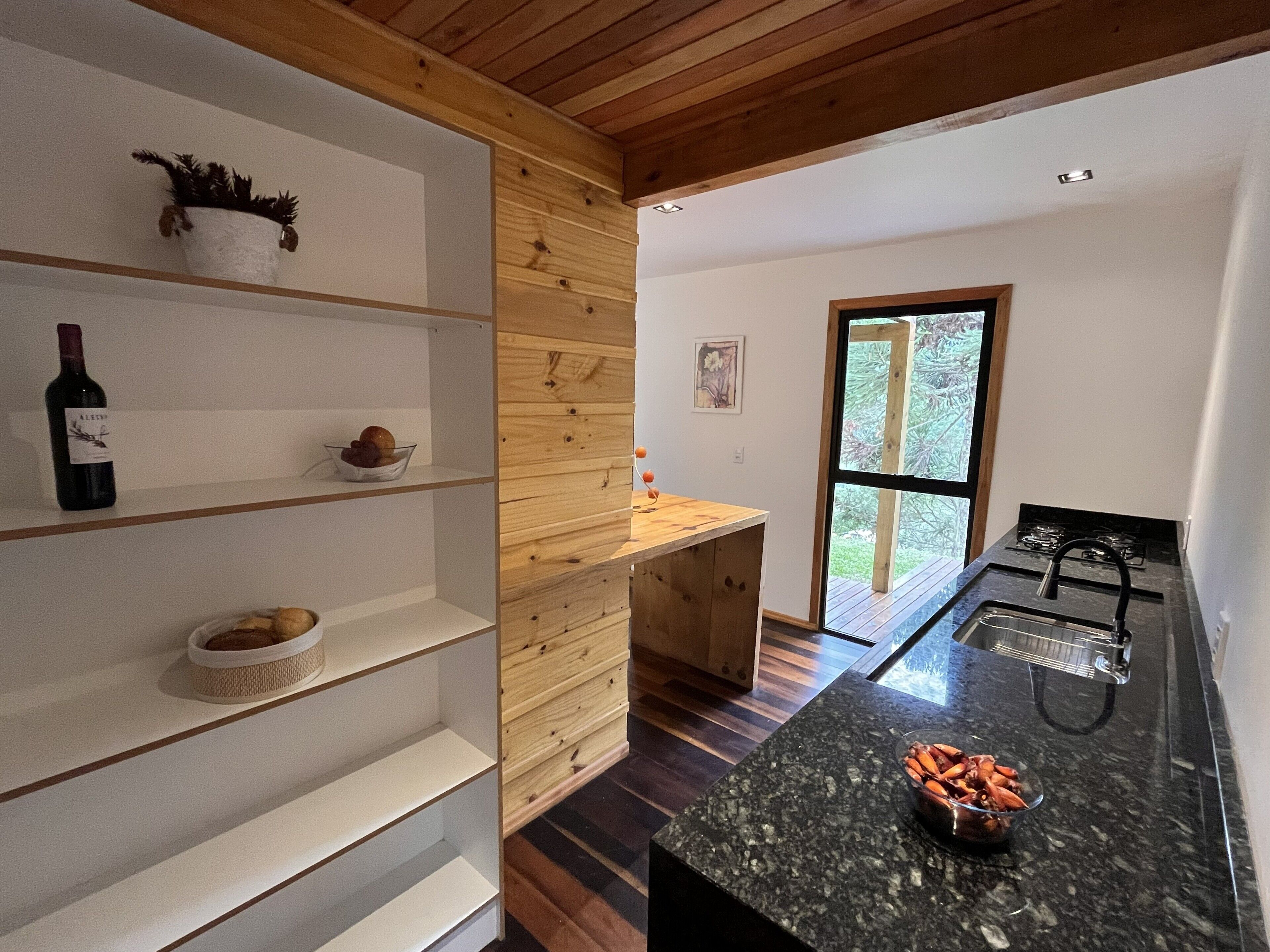 Eine moderne Küche mit Holzböden, einer Arbeitsplatte mit einer Schüssel voller Snacks und Blick durch ein großes Fenster.