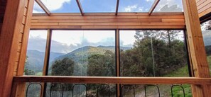 A wooden-framed window with a view of a mountainous landscape.