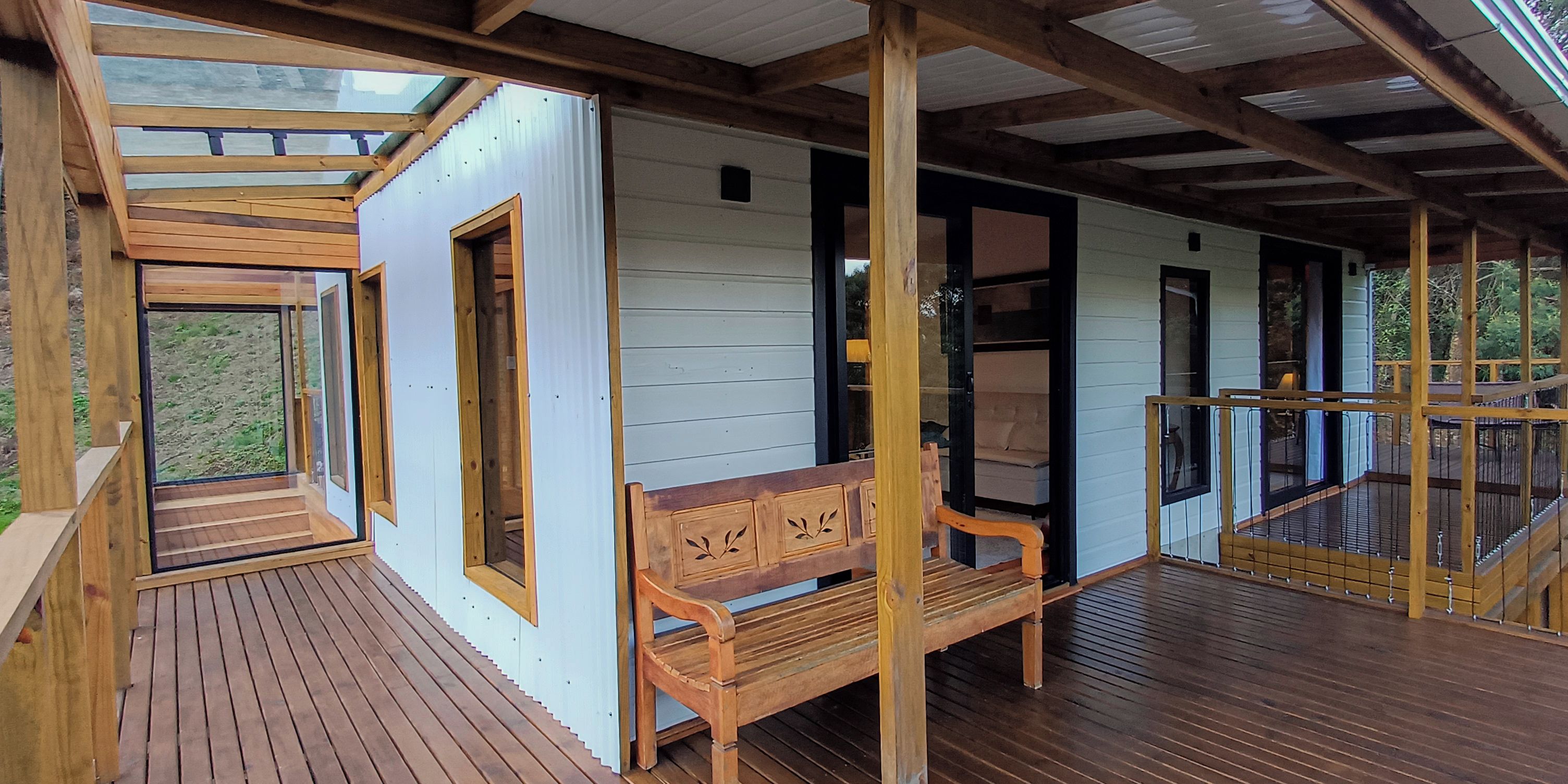 Eine Holzterrasse mit einer Bank und einer Glastür zu einem weißen Gebäude.