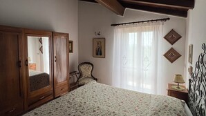 Une chambre avec un grand lit, une armoire en bois et une chaise.