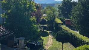 Un jardin avec un chemin de pierres, un petit arbre et un bâtiment doté d’un toit en tuiles.