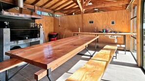 Uma cozinha ampla com uma longa mesa de madeira, forno embutido e pia.