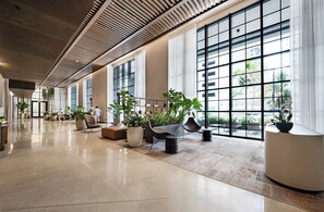 Eine großzügige Lobby mit großen Fenstern, moderner Sitzgelegenheiten und Zimmerpflanzen.