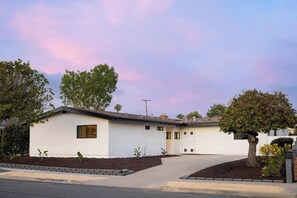 A single-story house with a flat roof, a front entrance, and a driveway leading to the garage. - The Horizon by Coastline Vacation Rentals (San Diego)