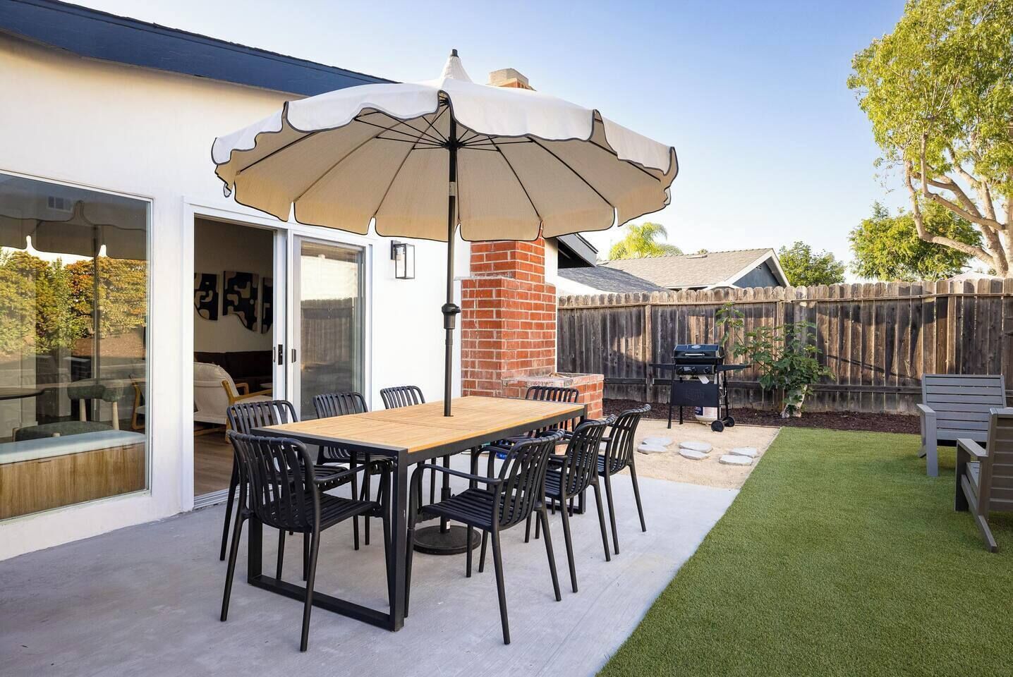 A patio with a table and chairs, a grill, and a covered umbrella.