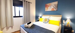 Une chambre d’hôtel avec un lit, une table de chevet avec une lampe et un tableau au mur.