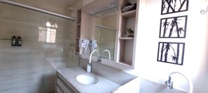 Une salle de bain moderne avec un grand miroir, deux lavabos, une douche et des toilettes.