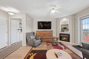 Una sala de estar con chimenea, televisor montado y ventilador de techo.