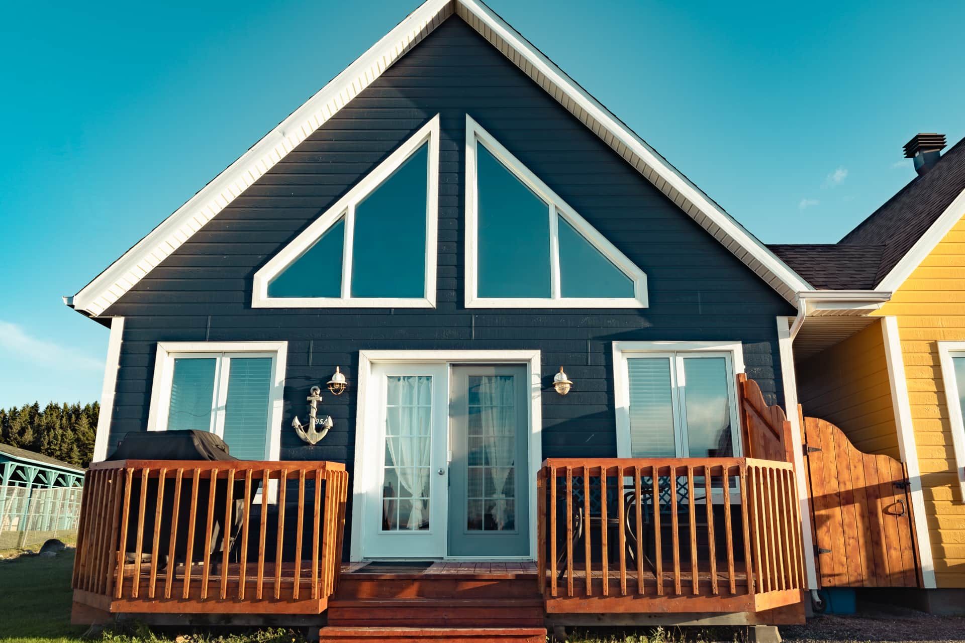 A two-story house with a dark blue exterior, white trim, and a front porch with wooden railings.