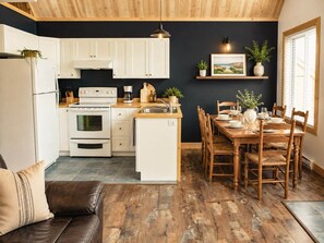 A modern kitchen with white cabinets, a built-in oven, and a dining area with wooden chairs and a table set for four.