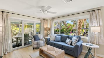 A spacious living room with a sofa, armchair, and a small table.