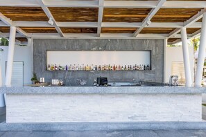 Eine Bar mit einer langen Flaschenregal, einer Theke und einer modernen Deckenkonstruktion.