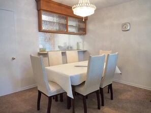 Ein Esszimmer mit Tisch und Stühlen, einer Kandelaber und einer Wanduhr.