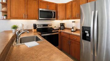 A modern kitchen with stainless steel appliances, wooden cabinets, and a granite countertop.