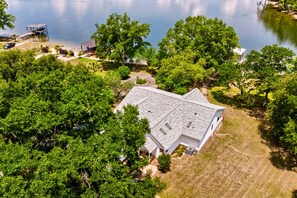 A house with a sloped roof, surrounded by dense greenery and a body of water. - Lake Wateree home with your own private dock and ramp.  Pet friendly with a fee. (Liberty Hill)