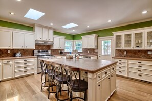A spacious kitchen with a central island, bar stools, and a view of the outdoors through large windows. - Lake Wateree home with your own private dock and ramp.  Pet friendly with a fee. (Liberty Hill)
