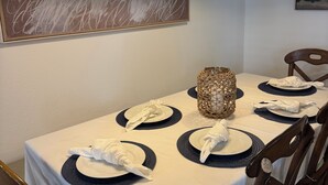 Mesa de jantar posta com pratos, guardanapos e um arranjo decorativo.