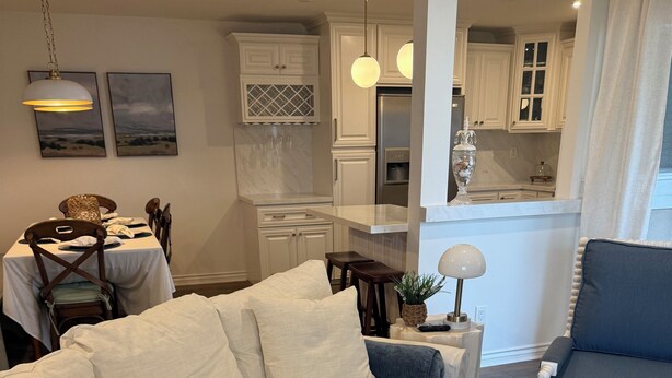 Uma sala de estar com um sofá branco, uma poltrona azul e uma mesa de centro com objetos decorativos.