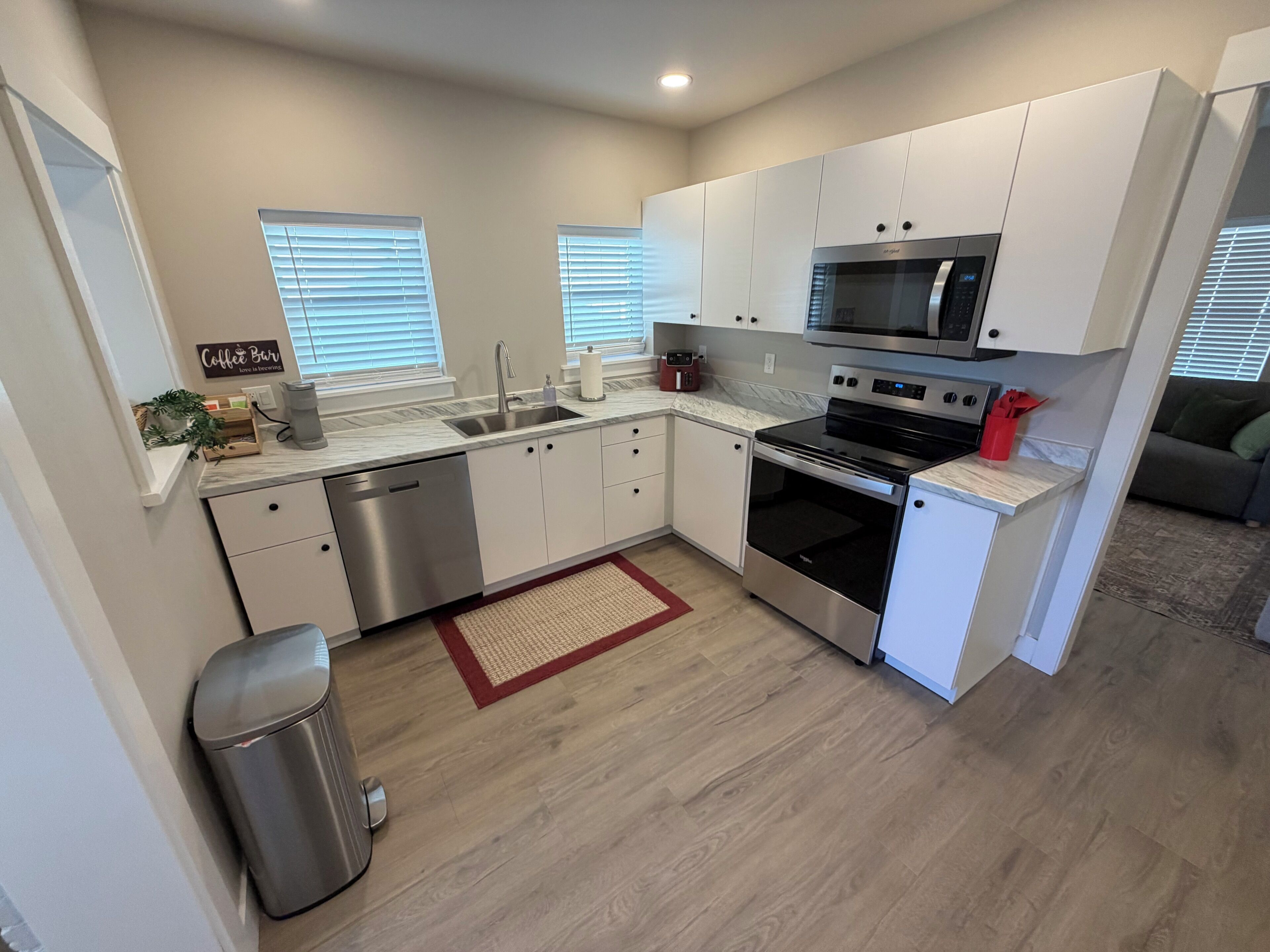 A compact kitchen with white cabinets, a stainless steel dishwasher, a microwave, and an oven.