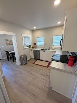 A compact kitchen with a sink, countertop, and a red rug.