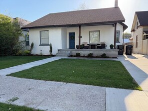 A single-story house with a front porch, a door, and a small garden area.