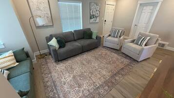 A living room with a grey sofa, a patterned rug, and two armchairs.