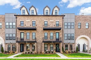 A row of townhouses with brick facades, multiple windows, and a flat roof. - Luxury Massive Townhome, Pool, Private Elevator, Amenities in Murfreesboro (Murfreesboro)