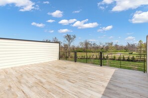 Eine Holzterrasse mit Blick auf eine grüne Landschaft und Bäume.