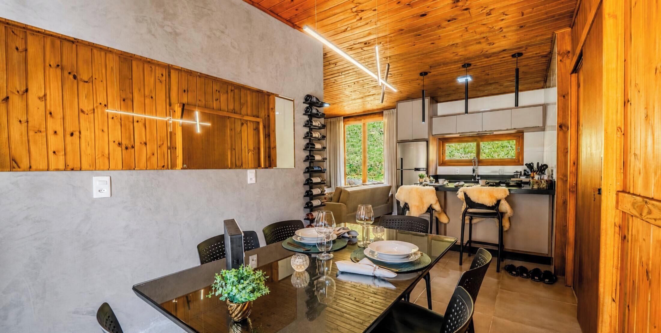 A dining area with a wooden ceiling, a table set for four, and a wine rack against the wall.