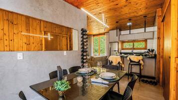 A dining area with a wooden ceiling, a table set for four, and a wine rack against the wall.
