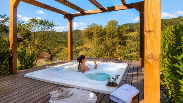 Una terraza de madera con un jacuzzi, un par de sandalias y una toalla.