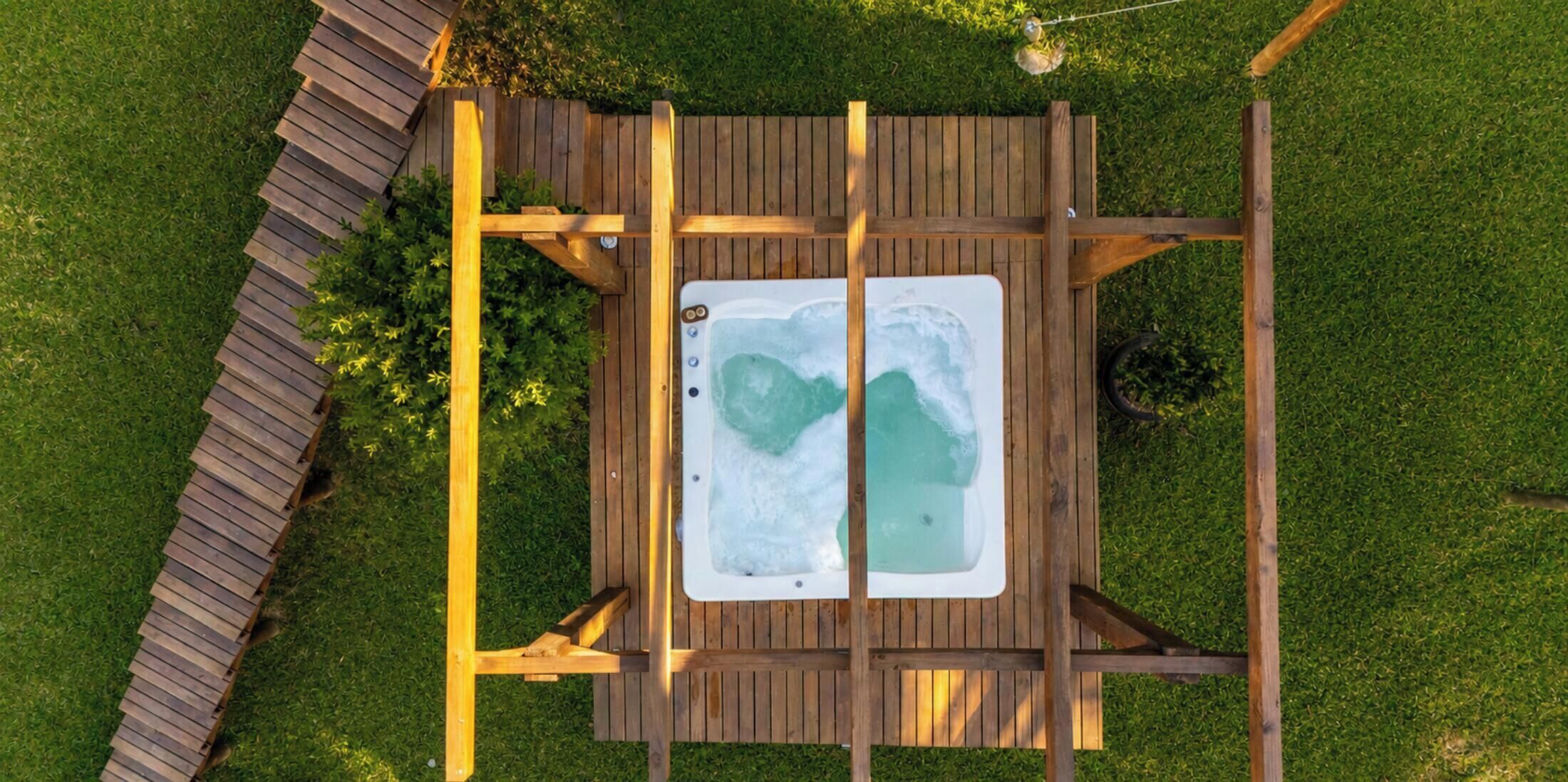 A hot tub on a wooden deck surrounded by grass.