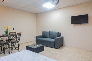 A furnished room with a sofa, a dining table with chairs, a small coffee table, and a flat-screen TV mounted on the wall. - Walk to Beach & Dining: Uvita Studio w/ AC & WiFi (Uvita)