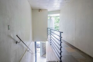 A corridor with a handrail, a door leading outside, and a view of greenery through a window. - Walk to Beach & Dining: Uvita Studio w/ AC & WiFi (Uvita)