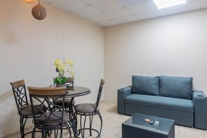 A living area with a round table, four chairs, a sofa, and a small coffee table with a phone and remote. - Walk to Beach & Dining: Uvita Studio w/ AC & WiFi (Uvita)