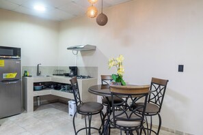 A compact kitchen with a built-in microwave, gas stove, and a small dining area with a round table and four chairs. - Walk to Beach & Dining: Uvita Studio w/ AC & WiFi (Uvita)