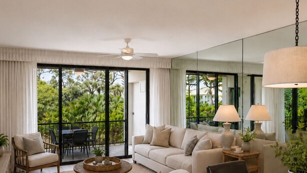 Uma sala de estar moderna com um conjunto de sofás, uma mesa de jantar e uma varanda com mobiliário de exterior.
