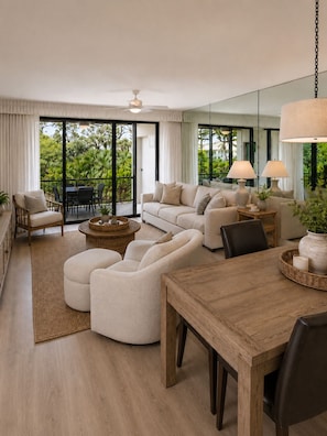 Ein modernes Wohnzimmer mit einer Sofagarnitur, einem Esstisch und einem Balkon mit Gartenmöbeln.