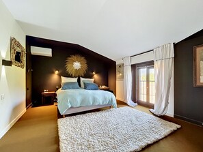 A bedroom with a bed, bedside tables, a large mirror, and a view through a sliding door.
