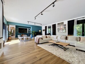 Un salon moderne avec un canapé blanc, une table basse et un coin repas comprenant des chaises et une table.