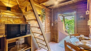 A wooden cabin interior with a wooden staircase, a dining area with a table set for two, and a view of greenery outside. - Magic Cabin Near Beto Carrero Trs0002 (Penha)