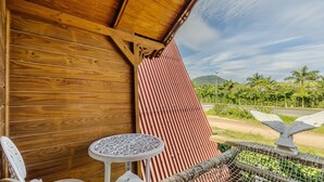 A wooden exterior wall with a corrugated metal roof, a small round table, and a decorative metal fence. - Magic Cabin Near Beto Carrero Trs0002 (Penha)