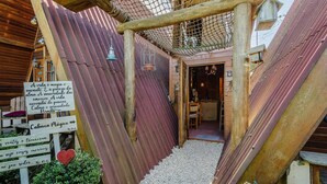 A rustic wooden structure with a corrugated metal roof, a wooden staircase, and a sign with Portuguese text. - Magic Cabin Near Beto Carrero Trs0002 (Penha)