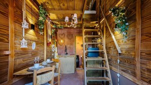 A cozy wooden cabin interior with a dining area, a staircase, and a small kitchen. - Magic Cabin Near Beto Carrero Trs0002 (Penha)