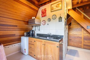 A compact kitchen with wooden walls, a built-in sink, and a small refrigerator. - Magic Cabin in Front of Beto Carrero - Trs0003 (Penha)