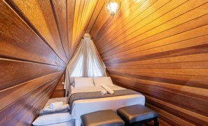 A room with a wooden slat ceiling, a bed with pillows and a rolled towel, and a bench. - Magic Cabin in Front of Beto Carrero - Trs0003 (Penha)