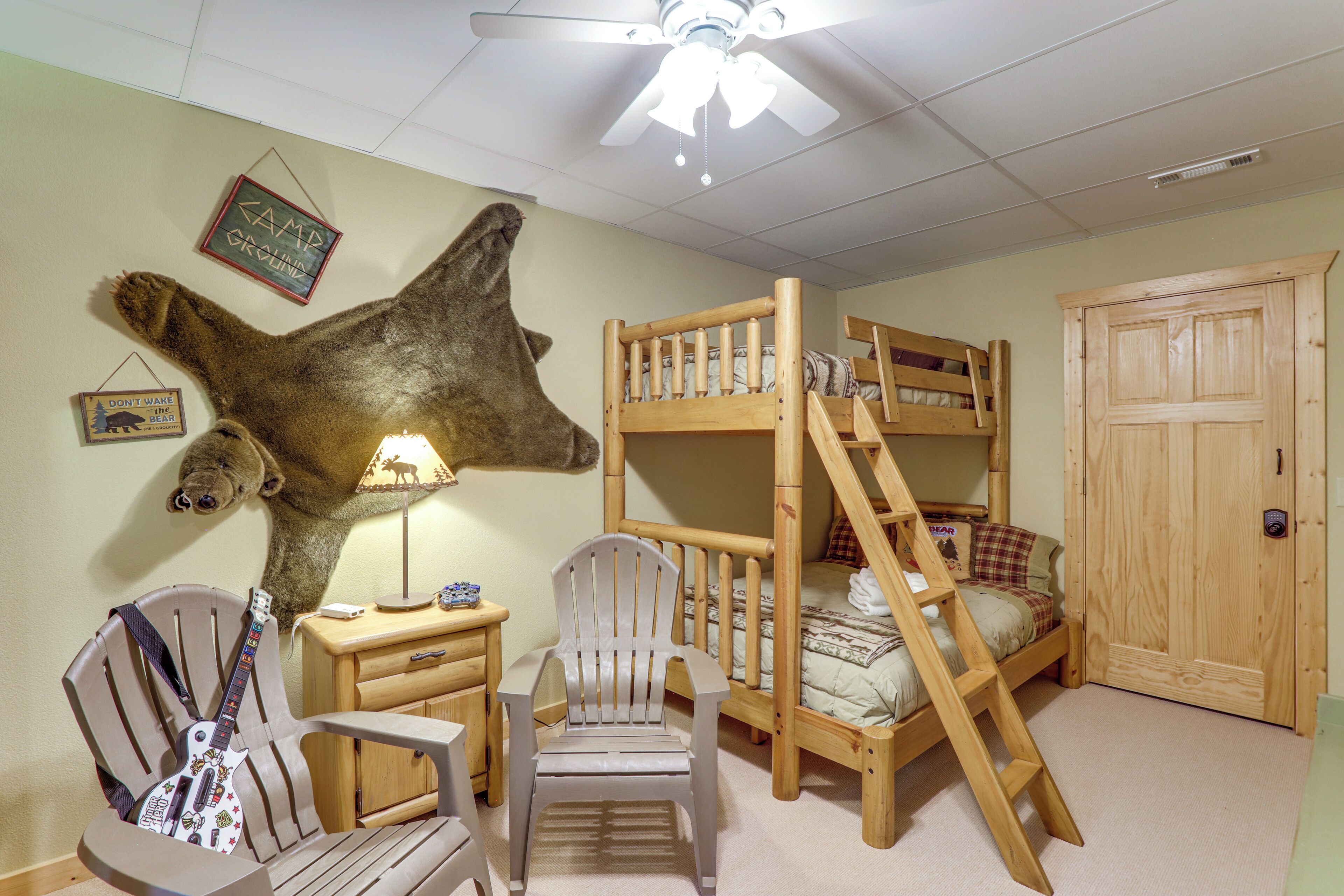 A child's room with bunk beds, a ceiling fan, a mounted animal head, and a guitar.
