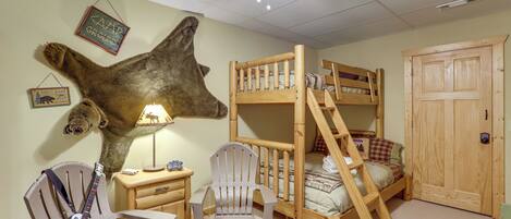 A child's room with bunk beds, a ceiling fan, a mounted animal head, and a guitar.