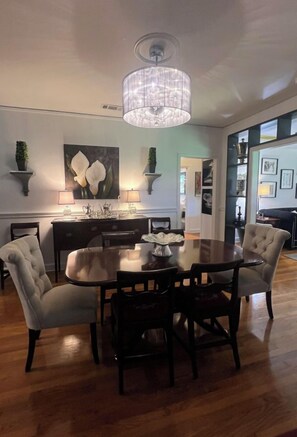 A dining area with a round table, chairs, and a chandelier.